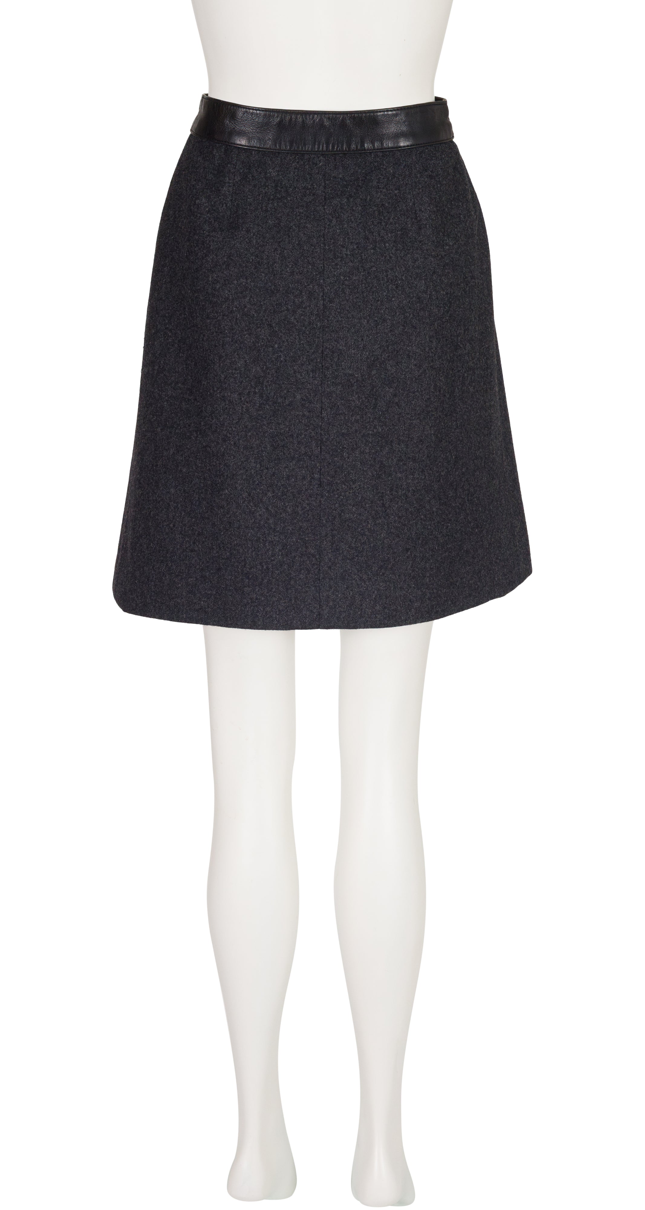 A 1970s Hermes dark charcoal gray A-line skirt with a black faux-leather waistband, displayed on a white mannequin against a white background.