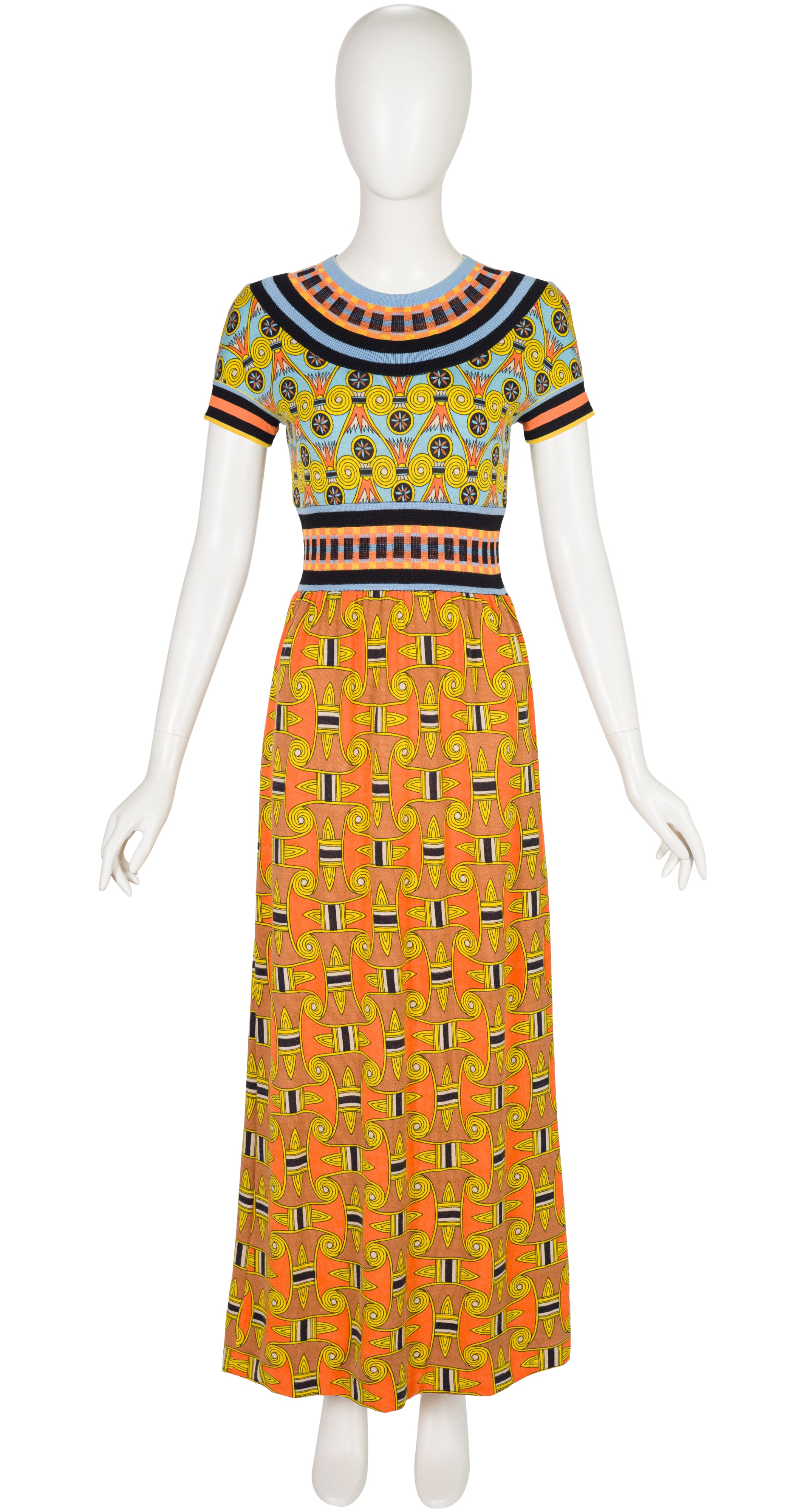 A 1970s Goldworm short-sleeve maxi dress with a colorful geometric and tribal-inspired print, displayed on a white mannequin against a plain white background.