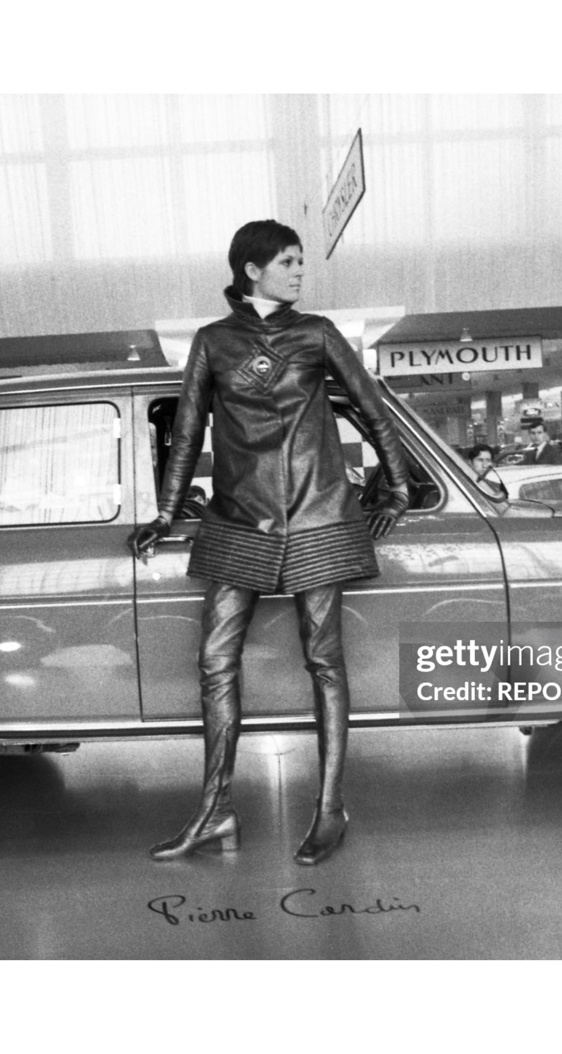 Woman wearing a Pierre Cardin leather coat in front of a car in 1969