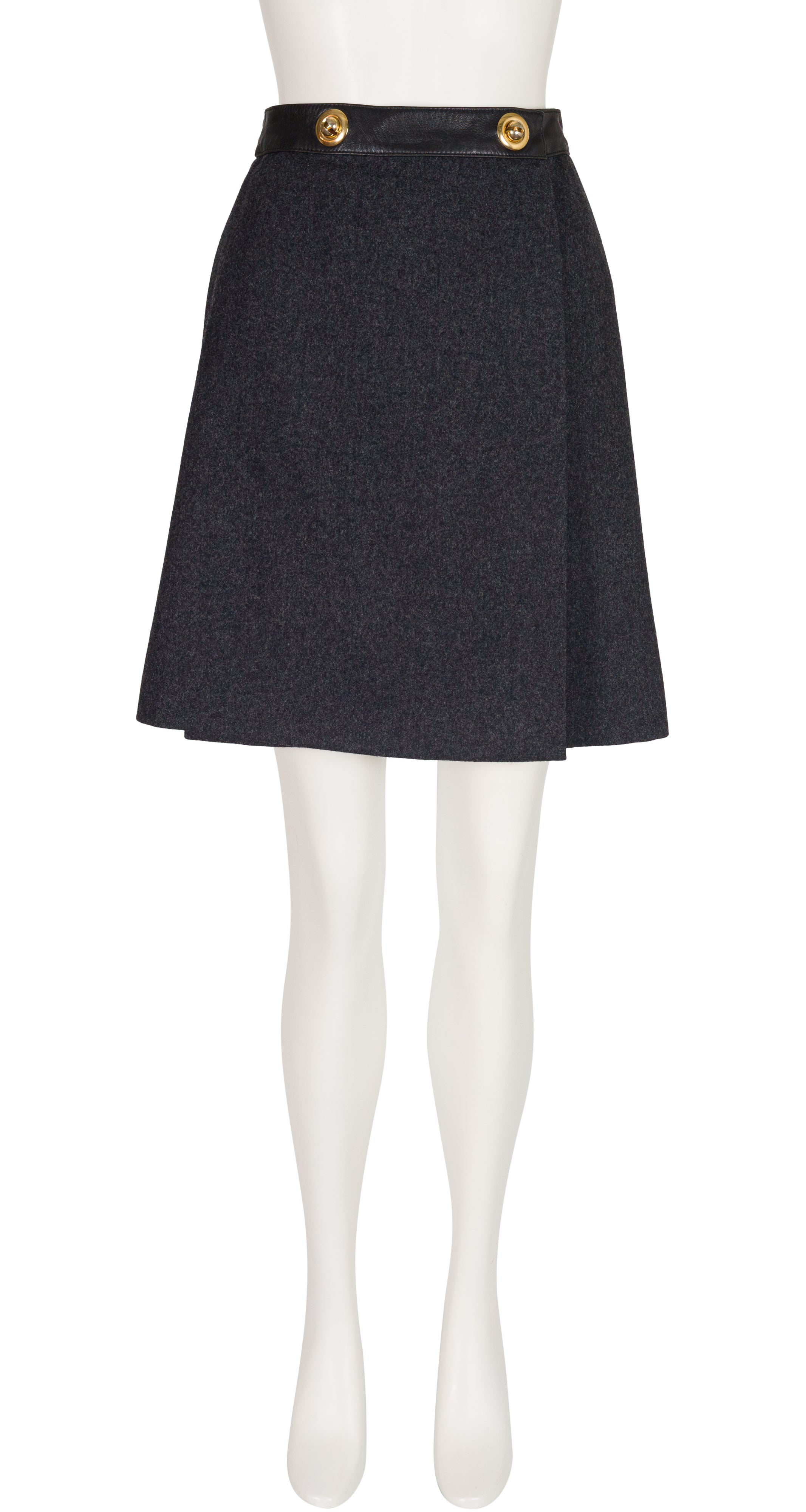 A 1970s Hermes dark charcoal gray textured A-line skirt with a black waistband and two gold buttons, displayed on a white mannequin.