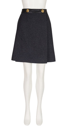 A 1970s Hermes dark charcoal gray textured A-line skirt with a black waistband and two gold buttons, displayed on a white mannequin.