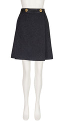 A 1970s Hermes dark charcoal gray textured A-line skirt with a black waistband and two gold buttons, displayed on a white mannequin.