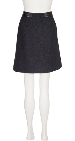 A 1970s Hermes dark charcoal gray A-line skirt with a black faux-leather waistband, displayed on a white mannequin against a white background.