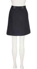 A 1970s Hermes dark charcoal gray A-line skirt with a black faux-leather waistband, displayed on a white mannequin against a white background.