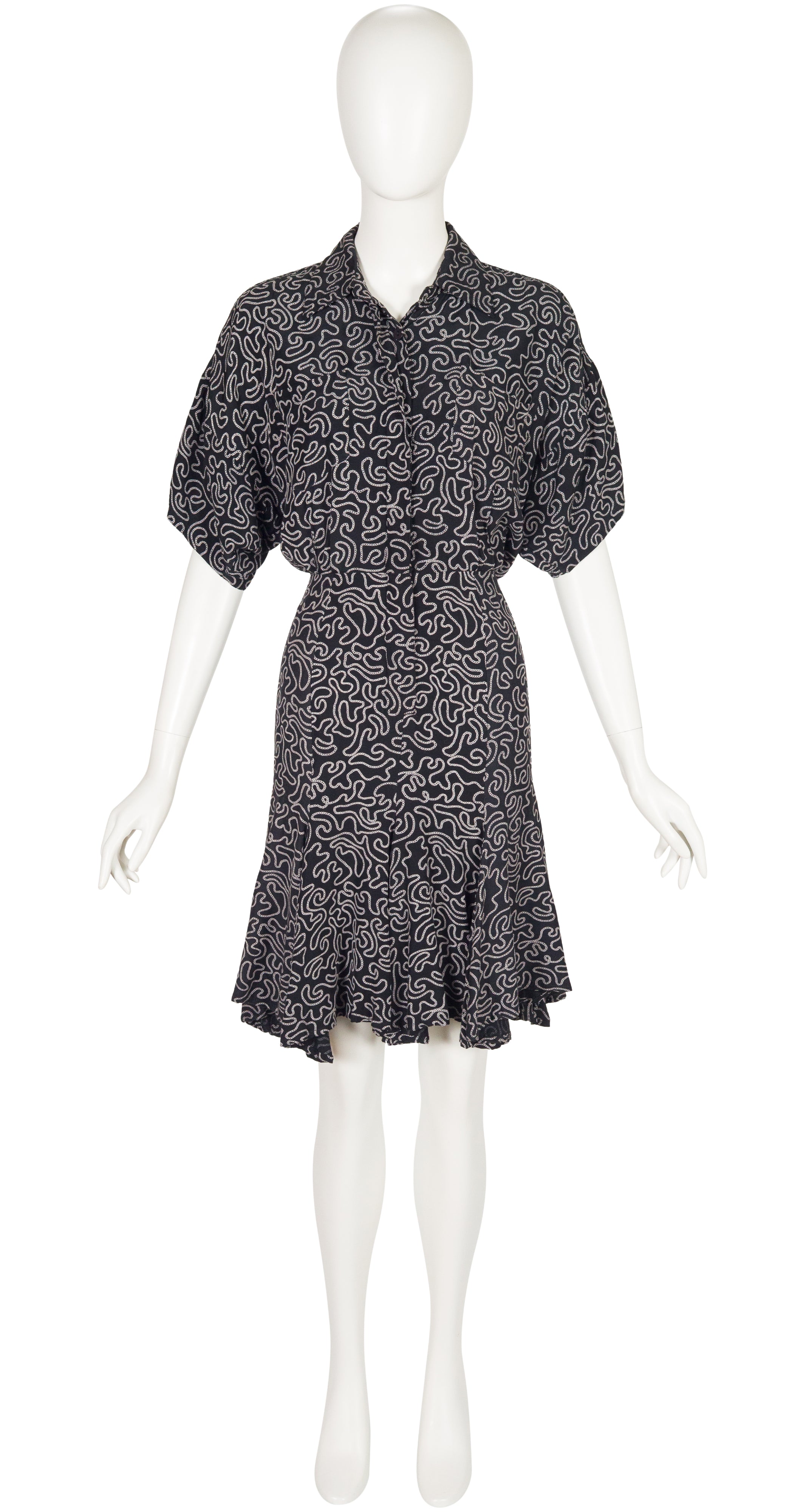 Black patterned dress on a white mannequin against a white background