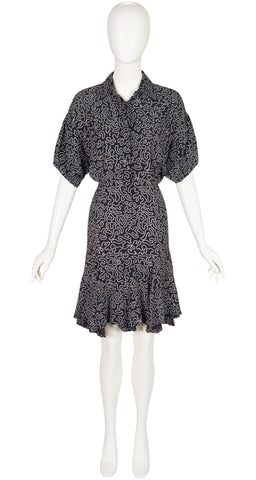 Black patterned dress on a white mannequin against a white background