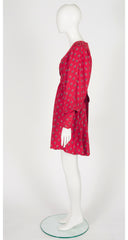 A 1970s Jeff Banks red wrap-style dress with a small repeating floral pattern, displayed on a white mannequin against a light gray studio background.